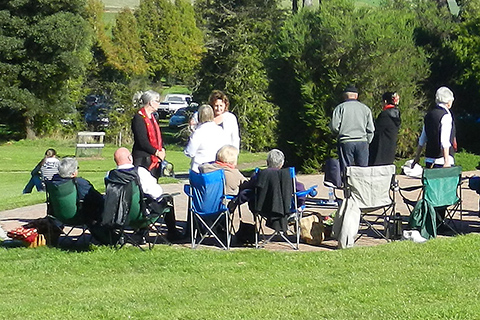 A group of people, some in chairs and some standing, enjoying the outdoors at The Tasmanian Arboretum