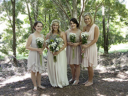 A bride and her three attendants posing in the shade of a tree